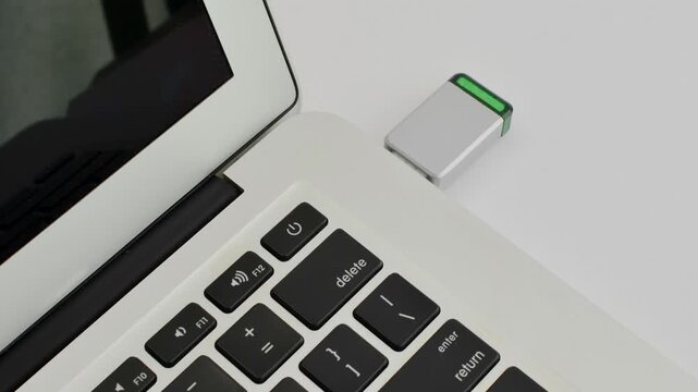 Detail of a USB drive next to a laptop, representing portable technology and fast data transfer.