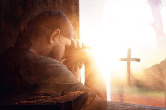 Young man praying from window. religion concept.