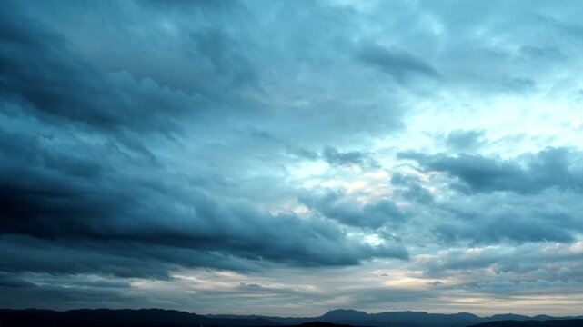 Dramatic dark storm clouds gathering over a distant mountain range under a moody sky, creating an atmospheric and intense natural scene