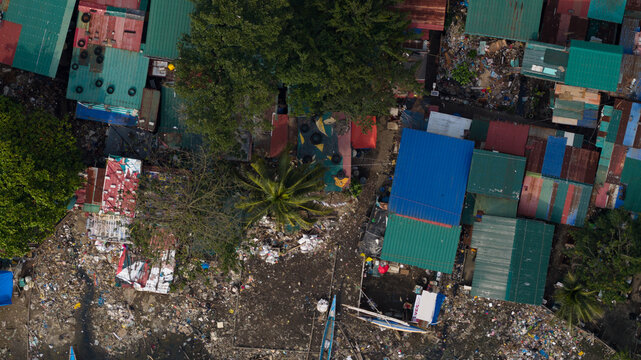Aerial view of houses amidst green trees and garbage, with colorful rooftops creating a vibrant yet contrasting scene, Navotas, Metro Manila, Philippines.