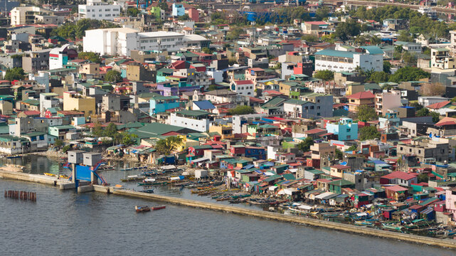 Aerial view of brightly colored buildings nestled tightly together along the coastline where the land meets the sea, Navotas, Metro Manila, Philippines.