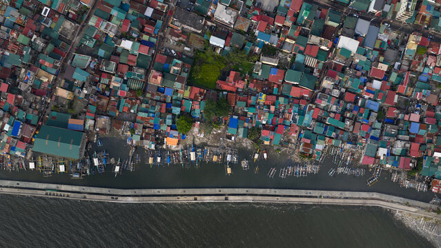 Aerial view of boats clustered along the breakwater, contrasting with the vibrant patchwork of colorful rooftops, Navotas, Metro Manila, Philippines.