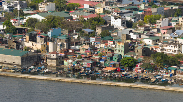 Aerial view of colorful rooftops and boats line the shore, contrasting with the calm sea, a vibrant tapestry of urban life., Navotas, Metro Manila, Philippines.