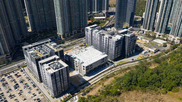 Aerial view of the modern data center complex, contrasted by the surrounding dense residential towers and a strip of green vegetation, Tseung Kwan O, New Territories, Hong Kong.