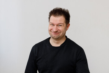 Isolaed man with tousled hair in black t-shirt makes a face.