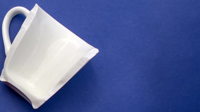 Detail of a broken white porcelain cup, symbolizing the poetry found in imperfection. Close-up of a broken white porcelain cup, expressing beauty in fragility on a light surface.