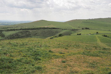 Obraz premium Scenic landscape from the Neolithic earthworks of Knap Hill across the Wiltshire countryside toward the historic Adams Grave long barrow under a summer sky, Wiltshire, UK