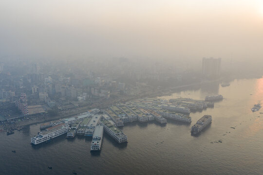 Aerial view of vessels docked on the riverbank, shrouded in a misty veil, creating a serene yet bustling harbor scene, Dhaka, Dhaka Division, Bangladesh.