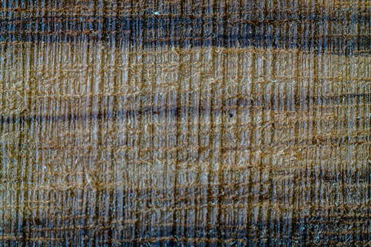 Extreme close up macro of rough sawn ovangkol hardwood plank showing raw timber grain and natural saw marks. Untreated exotic wood surface ideal for rustic woodworking or texture backgrounds.