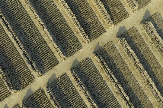 Aerial view of rows of bricks laid out under the sun, creating a textured mosaic of light and shadow, Dhaka, Dhaka Division, Bangladesh.
