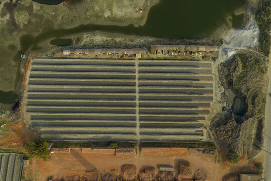Aerial view of a brickyard displaying rows of bricks contrasted by the surrounding landscape of soil and water, Dhaka, Dhaka Division, Bangladesh.