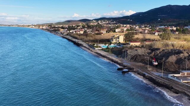 Aerial landscape of North Corfu coast featuring Acharavi village, mountains, and coastal road next to blue sea in Greece