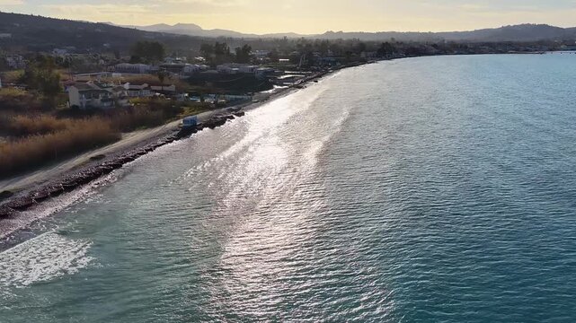 Aerial view of Acharavi Roda beach coastline with shimmering sea waves and coastal road during sunset in North Corfu, Greece