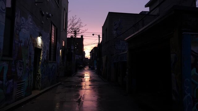 Dark industrial graffiti alley. Wet pavement and purple sunset sky. Toronto. 4K.