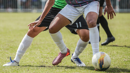 Fototapeta premium Two soccer athletes battling for possession during competitive football match on outdoor grass field, capturing movement, strength, agility, teamwork