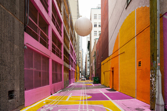 "Pink Alley" in Downtown Vancouver, British Columbia, Canada - Ancient dirty alleyway transformed into a vibrant street art project with a giant ball and basketball hoops