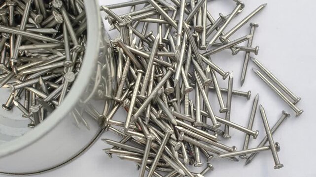 Close-up of many nails on a white surface, representing construction and manual labor concepts. White surface covered with detailed nails, representing an intriguing blend of order and chaos.