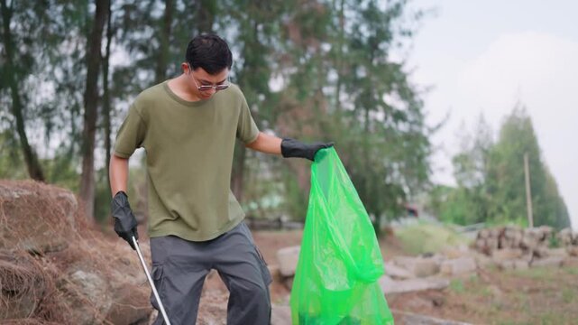 A dedicated environmentalist cleans up his surroundings. A man, wearing gloves, diligently picks up trash in a natural environment. This image evokes a sense of responsibility and environmental conser