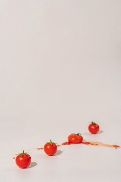 Fresh cherry tomatoes in a line on a light background, one of them is smashed