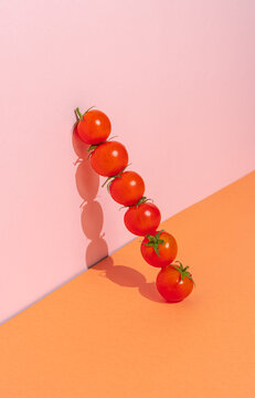 Fresh cherry tomatoes in a row on a pink and orange background. Minimalism