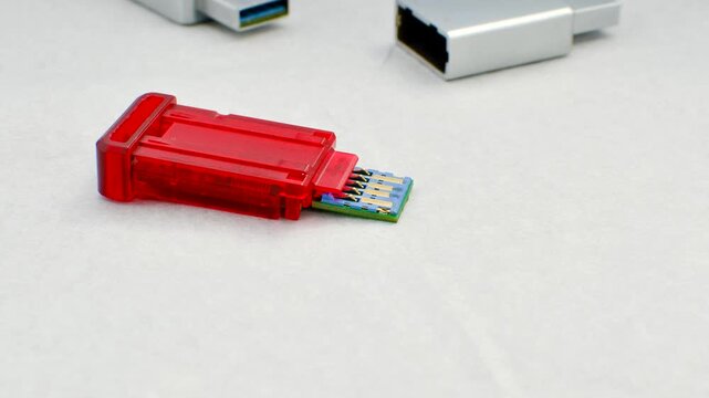 Close-up of a disassembled USB flash drive on a white background, revealing its internal complexity. Close-up of an open USB flash drive, exposing circuits and connections, on a white surface.