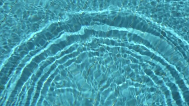 Clean swimming pool water footage with a wide curved ripple and sparkling light pattern. Minimal summer background for titles, branding, advertising and motion design.