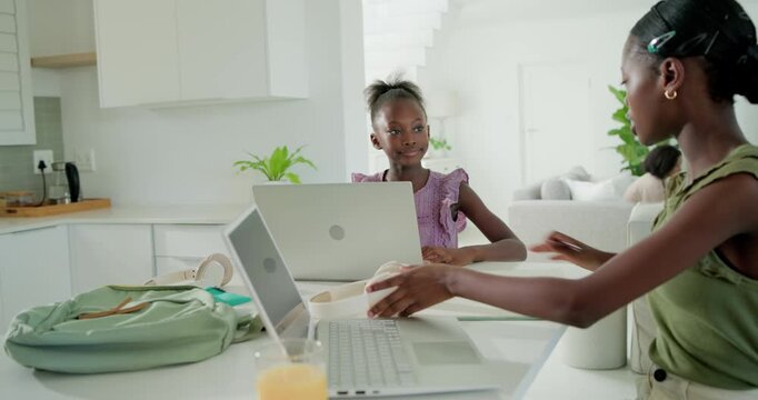 Removing headphones, African American teen sister guiding child at kitchen helping study on laptops