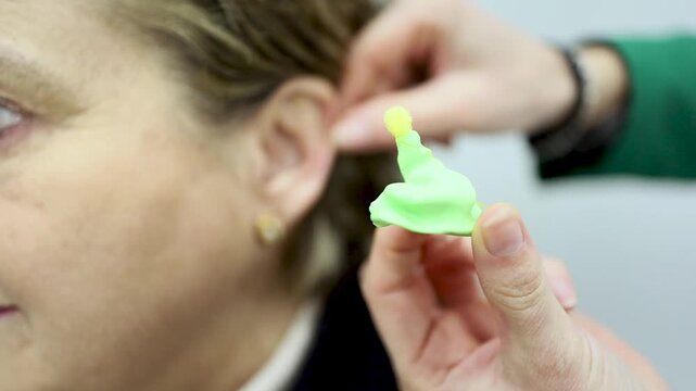 Video of an ENT specialist making a mold for an elderly woman's earplugs. Concept of earplug molds for noise reduction.