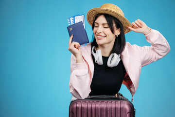 Smiling female traveler holding airline tickets on clean background, preparing for vacation. Travel...