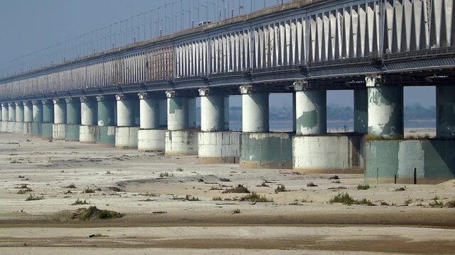 Concrete bridge over dry riverbed with sand and pillars