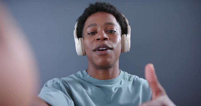 Male content creator reaching lens, starting recording, speaking, tapping headset to engage viewers