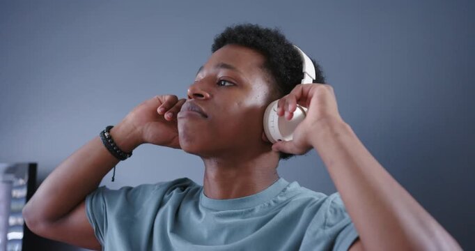 Man raising hands placing white over-ear headphones in room, adjusting cups testing fit and audio