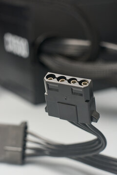 4-pin black molex power connector on gray surface, female peripheral hardware plug with metal pins, side view with soft focus, hardware power supply concept