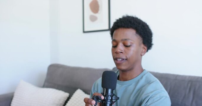 African American man adjusting shock mount, bringing mic near, speaking at home for podcast