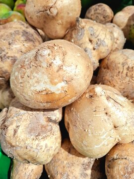 Fresh jicama, round in shape, is arranged in a plastic basket at a supermarket. Its local Indonesian name is "Bengkuang," and its scientific name is Pachyrhizus erosus.