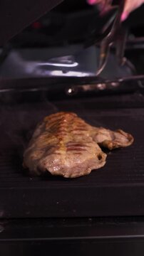 Cooking a steak. A professional chef prepares delicious meat on a hot grill