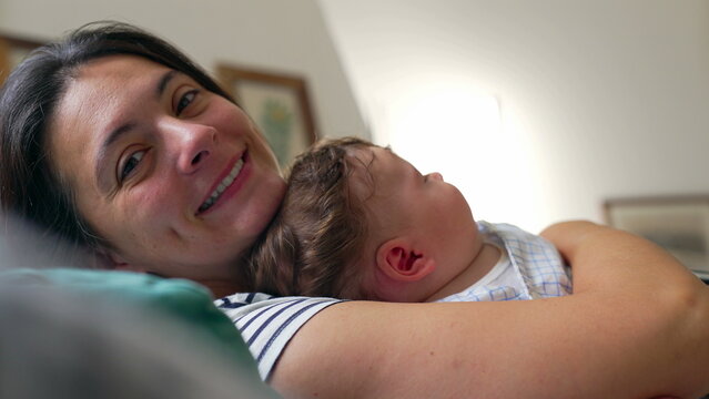 Mother smiling while holding baby, affectionate moment, joy, warmth, security, trust, family bonding, parent-child connection, happiness, nurturing embrace