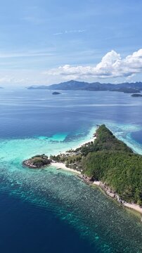 Cinematic aerial video in vertical portrait orientation of tropical island in the Philippines with palm trees and beautiful beach