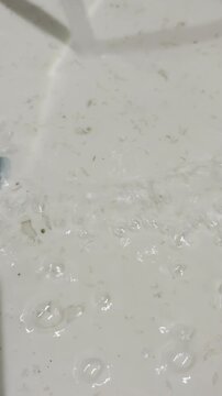 Water flowing in terrazzo sink with bubbles and subtle rainbow reflection. Clean, minimal background for skincare, hygiene, and wellness content.