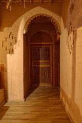 Obraz premium Corridor and wood doors of a modern, luxurious house in the Berber tradition of adobe wall, decorated in Amazigh symbols. Boumalne Dadès-Morocco-216