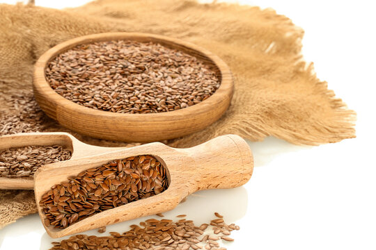Flax seeds with kitchen utensils on jute cloth, macro.