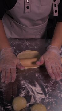 Kneading the pie dough. A woman rolls out the dough in the kitchen