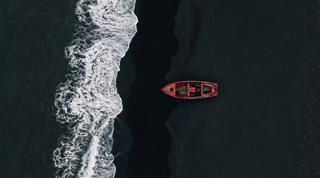Rustic red boat sails dark ocean with crashing waves in minimalist style