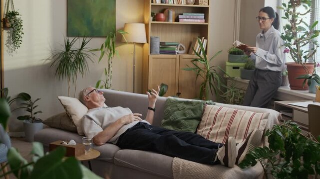 Full slowmo shot of senior Caucasian man lying on couch in cozy green office during individual therapy session and sharing feelings with middle-aged female psychologist holding notebook
