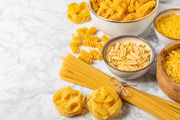 Assortment of uncooked Italian pasta in bowls on background. Variety of dry pasta, top view, food background. Different types of uncooked pasta. ingredients. flat lay. Assorted uncooked Italian pasta 