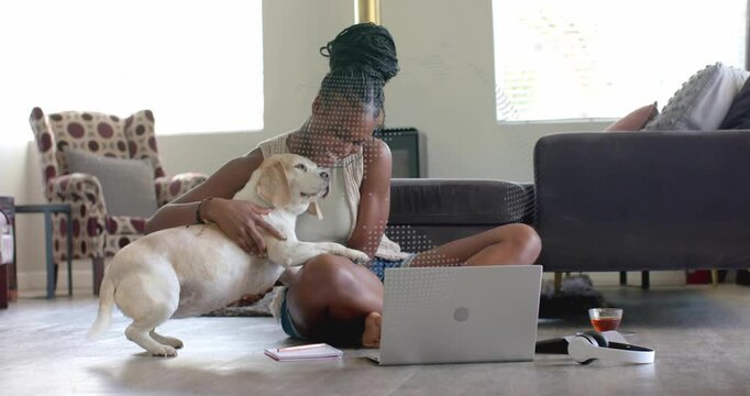 Woman working from home, laptop open, dog approaching placing paws, woman pausing work stroking dog
