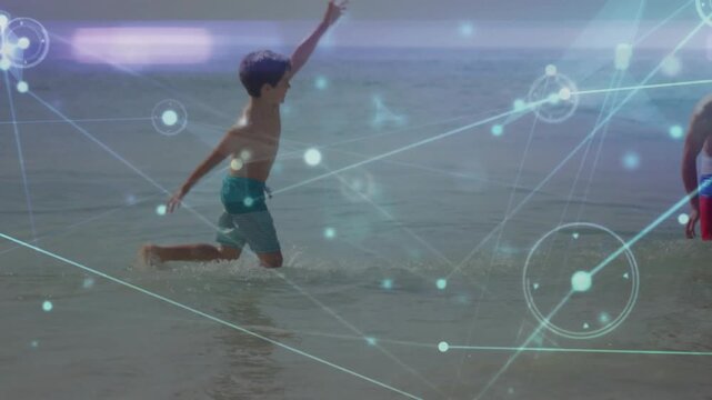 Father and son running and splashing in shallow water on beach wearing swim trunks, network overlay