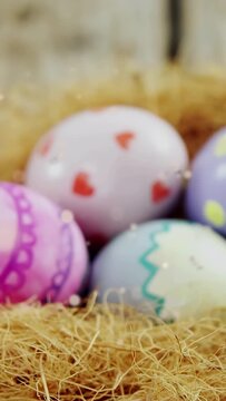 Vertical video: Pastel eggs in straw, camera pulling back, revealing patterns, bokeh for decor