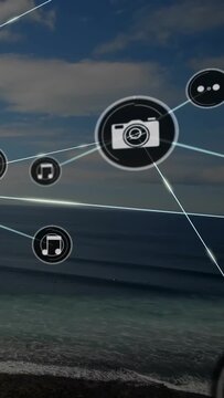 Vertical video: Popping UI node sparking camera and music nodes scaling over sea for tech