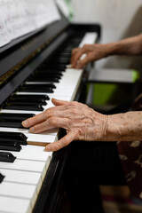 Fototapeta premium an old person's hands playing piano, close-up of hands, in a home environment